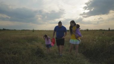 Küçük tatlı kızıyla mutlu ve çekici ebeveynler ve yeşil arazide yürüyen neşeli ergen kız çocuğu yaz tatilleri boyunca kırsal alanda hobi ve manzaranın tadını çıkarıyorlar..