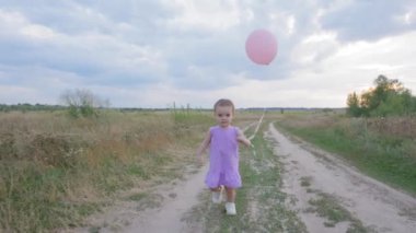 Sevimli bebek balon tutarken, kırsal yolda yürürken, mutluluk ve tasasız ruh halini ifade ederken, kırsal kesimde yaz tatillerinin keyfini çıkarırken,.