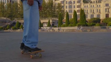 Şehir sokağında kaykayla kaykay süren, aktif yaşam tarzı hippi erkek kaykaycı. Yakın plan..