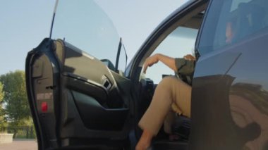 Yakışıklı Afro-Amerikan erkek sürücü portresi günlük giysiler içinde araba kapısını açıyor ve güneşli bir günde dostça gülümsüyor, şehir gezisi sırasında pozitifliğini ve mutluluğunu ifade ediyor..