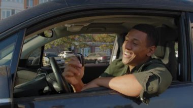 Heyecanlı çekici siyah erkek sürücü, elinde anahtarsız giriş anahtarı, araba galerisinde araba aldıktan sonra mutluluk ve neşe ifade ediyor..