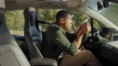 Afro-amerikan erkek sürücü şehir trafiğinde araba kullanıyor, araba yolculuğunda motorlu taşıt kazası geçiriyor, trafik kazalarında kafa karışıklığını ve şoku gösteriyor..