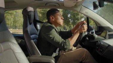 Şehir trafiğinde araba kullanan siyahi bir erkek sürücü, acil durum freni yapıyor ve yolda kaza yapmaktan kaçınıyor, kızgınlık ve hayal kırıklığını dile getiriyor..