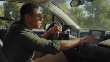 Çekici Afrikalı Amerikalı erkek sürücünün portresi, yolculuk güzergahını bulmak için arabada oturuyor, yolculuk yaparken modern GPS navigasyon sistemi kullanıyor..