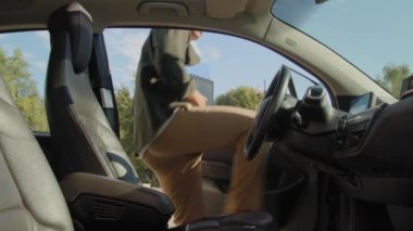 Kendine güvenen Afro-Amerikan iş adamı. Günlük giysiler içinde arabaya giriyor, emniyet kemerini takıyor ve şehirde yolculuk sırasında elektrikli araç kullanırken motor çalıştırma düğmesine basıyor..