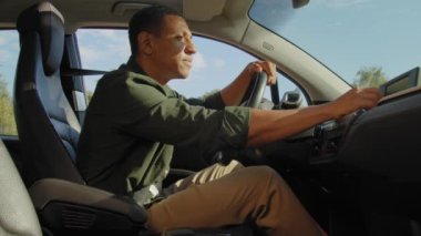 Çekici siyah erkek sürücü şık günlük giysiler içinde seyahat gps navigatör haritasını kullanarak seyahat rotasını seçiyor, iş seyahatinde araba kullanırken en iyi rotayı arıyor..