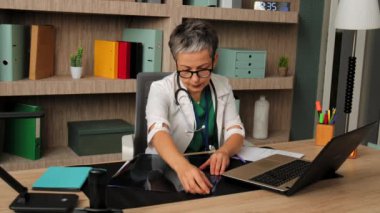 Yoğunlaşmış kadın doktor travmatolog. İnsan omurgasının röntgenini inceliyor. Klinikte çalışırken kikofotik dereceleri ve açıları ölçüyor.