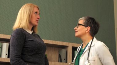 Üniformalı üst düzey kadın pratisyen hekimin tıp bürosundaki danışmanlık sırasında orta yaşlı kadın hastaya reçeteli tedaviyi açıkladığı doğru..