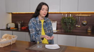 Gebelik sırasında vitamin ve takviye maddeleri alan ve bir bardak su içen hamile güzel bir kadın. Mutfaktaki hormon değişikliklerini dengelemek için.