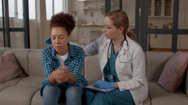 Üniformalı empatik kadın pratisyen doktor, hasta Afrikalı Amerikalı kadına destek veriyor ve onu teselli ediyor. Hastanın kısa süre sonra iyileşeceğine dair güvence veriyor..
