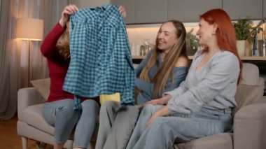 Alışveriş çantasından alışveriş yapan mutlu, orta yaşlı bir kadın, pozitif olgun bayan arkadaşlara yeni giysiler gösteriyor, ev içi alışveriş günlerini tartışıyor ve paylaşıyor..