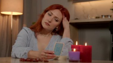 Kızıl saçlı orta yaşlı bir kadının portresi. Düşünceli ve konsantre. Geleceği tahmin ediyor ve geceleri mum ışığı odasıyla aydınlanarak tarot kartları okuyor..