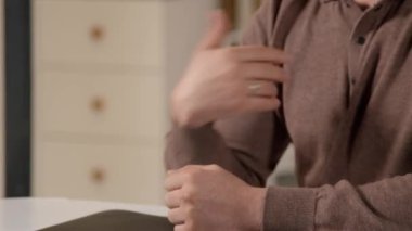 Yetişkin erkek ellerinin iletişim için işaret dilini kullanırken içeride arkadaşlarıyla konuşan engelli bir adamın yakın çekimi..