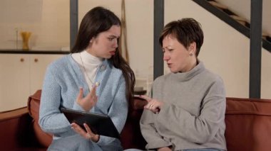 İşitme kaybı ve işitme engelli güzel bir anne ağıyla dijital tablet üzerinde çekici bir genç kız. Evde işaret dili kullanarak parti için kıyafet seçip tartışıyorlar..