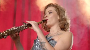 İlham verici kadın müzisyen portresi soprano saksafon çalıyor, sahnede canlı caz müzik yapıyor sahne ışıkları ve müzik kulübündeki duman bulutlarıyla aydınlatılıyor..