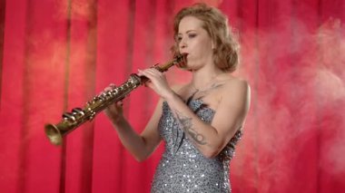 Zarif elbiseler içinde, doğaçlama giyinmiş, soprano saksafon çalan ve konser salonundaki spot ışıklarıyla aydınlatılmış sahnede caz çalan yetenekli, çekici kadın saksafoncu.