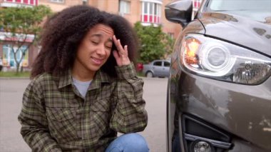 Hayal kırıklığına uğrayan ve üzülen Afro-Amerikan kadın sürücünün portresi şehir gezisi sırasında araba kazaları ve ezikleri kontrol ediyor..