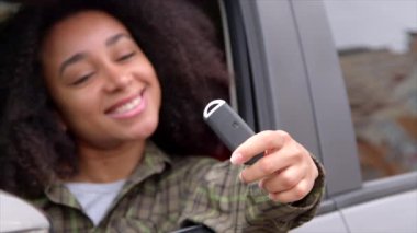 Neşeli, güzel, afro-amerikan kadın sürücü, otomobilde oturuyor, yeni arabanın anahtarsız giriş hareketsizleştiricisini gösteriyor, araba galerisinde alışveriş yaptıktan sonra heyecan ve mutluluğu ifade ediyor. Yakın plan..