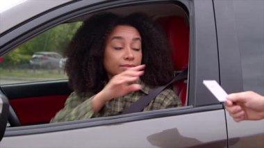 Afro saç stili güzel Afrikalı kadın sürücü trafik kontrolü sırasında ehliyetini polis memuruna verirken, kadın da yolda araba kullanıyordu..