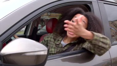 Agresif sinirli, güzel, Afro-Amerikan kadın sürücü trafik sıkışıklığında sıkışmış, arabanın camından birine bağırıyor, şehirde trafiğin yoğun olduğu saatlerde sinir ve öfke belirtileri gösteriyor..