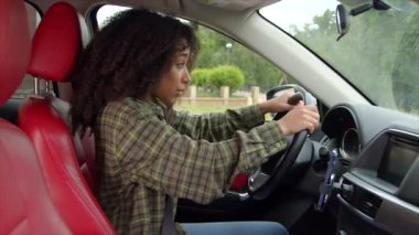 Güzel Afro-Amerikalı kadın sürücü şehir trafiğinde araba kullanıyor, araba yolculuğunda motorlu taşıt kazası geçiriyor, kafa karışıklığını ve şoku gösteriyor..