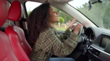 Sinirli Afro-Amerikan kadın sürücünün yan görüntüsü trafik sıkışıklığında sıkışmış, kornaya basan, şehirde yoğun yol üzerinde araç kullanırken el kol hareketi yapan ve tartışan.