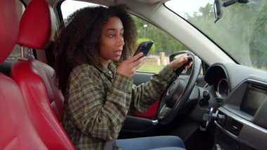 Trafikte trafikte araba sürerken, arabada oturan, cep telefonundan sesli mesaj kaydeden, şık saçlı, çekici bir kadın sürücü..