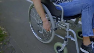 Park sokağında kırışık tekerlekli sandalyeyle gezen yaşlı bir kadının yakın çekimi. Bu arada aktif bir yaşam tarzı ve dışarıda eğlence amaçlı bir kovalamaca sürüyor..