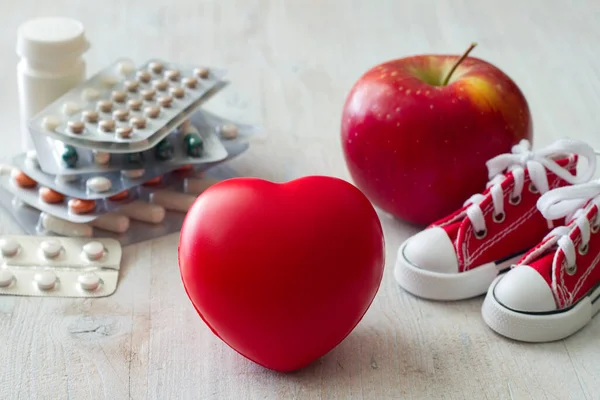 Heart medications, canvas shoes, apple and red heart, natural and medical remedies for healthy heart concept