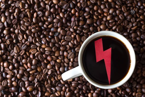 Red energy sign in cup of coffee on background of coffee beans, concept