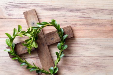 Wooden cross with sprigs of boxwood in heart-shaped, easter symbol of life, religious concept  clipart