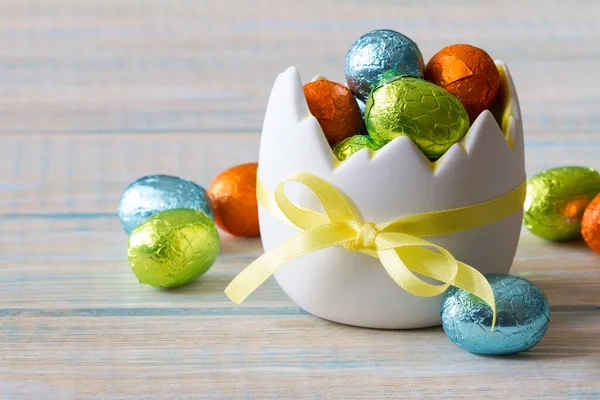 Chocolate easter egg in eggshell shaped bowl on light wooden background, easter sweets, decoration