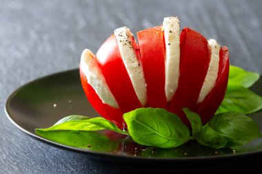 İçinde mozzarella dilimleri olan domates tabakta fesleğen yaprağı, caprese salatası, İtalyan yemeği konsepti.