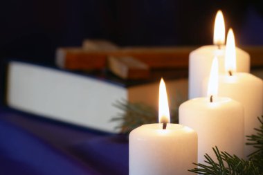 Dört tane İncil 'li ve arka planda haç şeklinde yanan Advent mumları, dini sembol kavramı.