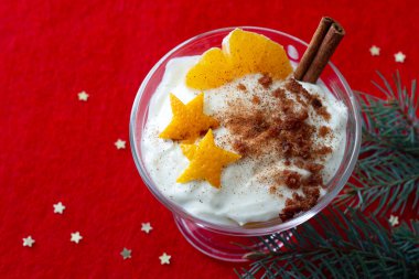 Noel tatlısı, portakallı zencefilli ekmek, krem şantili ve kırmızı arka planda tarçınlı.