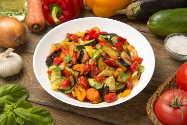 Beyaz arka planda izole edilmiş salata kasesinde sotelenmiş patlıcan kabağı havuç ve domates..