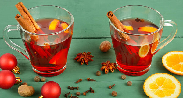 Mulled wine, orange and spices on a wooden table. Wide photo.