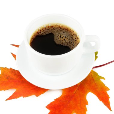 Beyaz arka planda izole edilmiş bir fincan kahve ve sarı akçaağaç yaprağı..