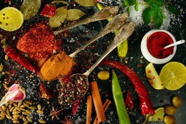 Karanlık bir masada bir sürü farklı baharat ve aromatik otlar. Yukarıdan görüntüle.