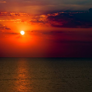 Deniz sahili ve kızıl güneş doğuyor. Parlak güzel arkaplan.