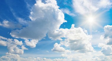 Beyaz bulutlu mavi gökyüzü ve parlak güneş. Geniş resim.
