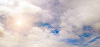 Beyaz bulutlu mavi gökyüzü ve parlak güneş. Geniş resim.