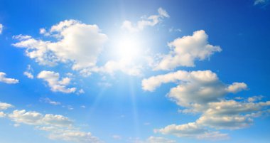 Beyaz bulutlu mavi gökyüzü ve parlak güneş. Geniş resim.