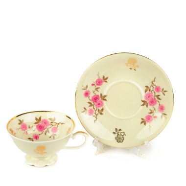 Beyaz arka planda izole edilmiş klasik porselen bardak ve çay tabağı. Metin için boş alan.