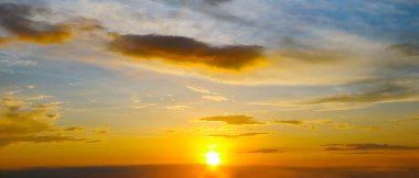 Bulutlu gökyüzü ve ufuk üzerinde parlak gündoğumu. Geniş fotoğraf.