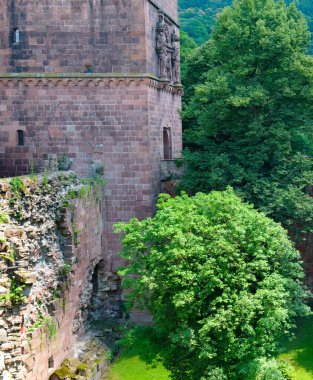 An ancient, partially ruined brick structure from Heidelberg Castle in Germany, with large arched windows framed by weathered stone. Vertical photo. clipart