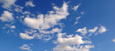 Açık mavi gökyüzü ve birkaç bulut. Gökyüzü çok parlak ve bulutlar her yere dağılmış. Geniş resim.