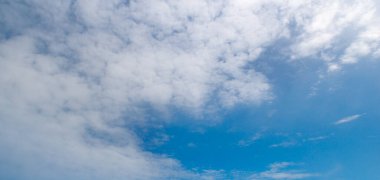 Yumuşak, beyaz bulutlarla dolu canlı, mavi bir gökyüzünün huzurlu ve geniş bir görüntüsü. Bu güzel doğal arka plan, metin için geniş bir alana sahip bir barış, özgürlük ve açıklık hissi veriyor..