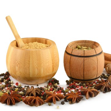 Temiz beyaz arka planda ahşap kaplar etrafında dizilmiş yıldız anasonu, biber ve hindistan cevizi içeren canlı bir baharat koleksiyonu. Bu resim yemek, yemek ve mutfak temaları için idealdir..