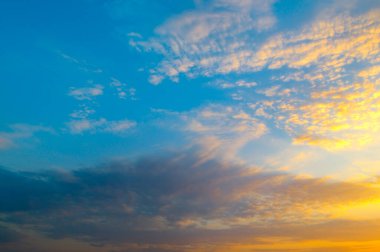 Canlı günbatımı gökyüzü, dinamik bulutlarla birlikte çarpıcı bir renk değişimini derin maviden parlak turuncuya yansıtır. Bu güzel, soyut resim geniş bir kopya alanına sahip ve doğa, seyahat veya ilham verici temalar için mükemmel..